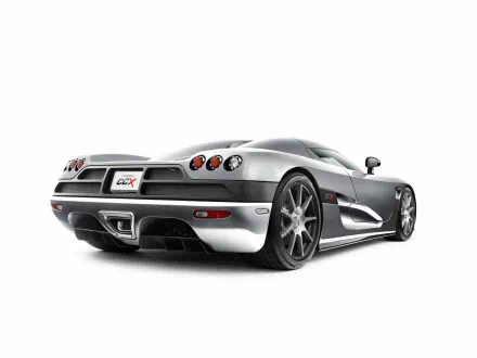 A sleek Koenigsegg CCX sports car showcased in a high-definition desktop wallpaper, featuring a striking silver exterior and dynamic rear view.