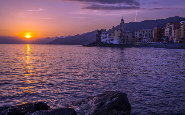 Sunset over the Ligurian Sea with a coastal town in Italy, featuring calm waters and a serene sky in this 4K Ultra HD desktop wallpaper.