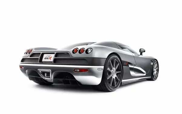 A sleek Koenigsegg CCX sports car showcased in a high-definition desktop wallpaper, featuring a striking silver exterior and dynamic rear view.