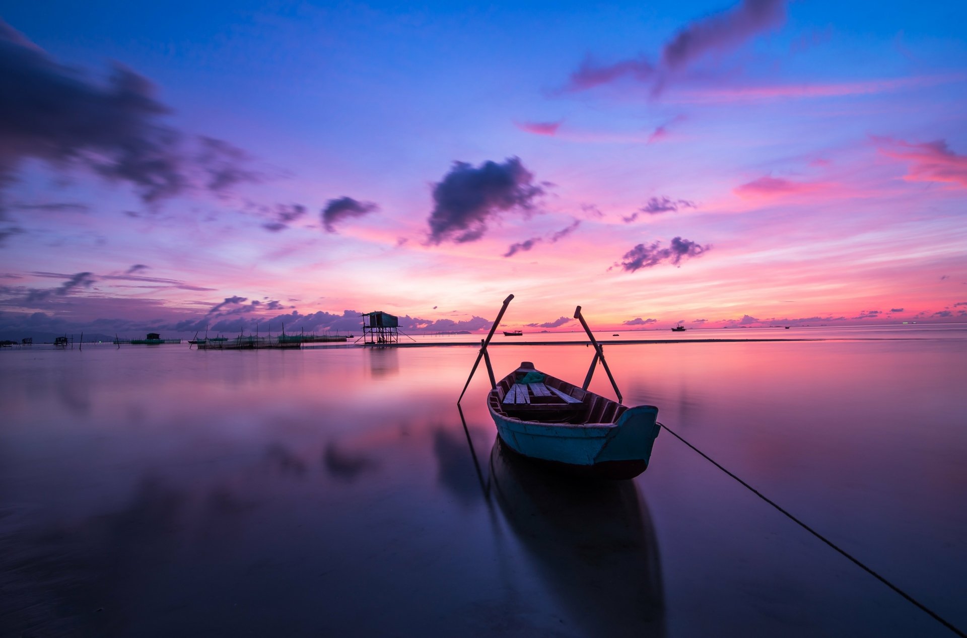 A serene lake at sunset with a boat anchored in calm waters, captured in stunning 4K Ultra HD for a vibrant PC desktop wallpaper.