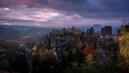 Sunset over the Elbe Sandstone Mountains in Germany, featuring the man-made Bastei Bridge amidst autumn forest colors, captured in 4K Ultra HD.