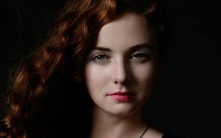 Close-up HD desktop wallpaper of Lena Katina, Russian redhead singer from t.A.T.u., with soft lighting highlighting her face against a dark background.