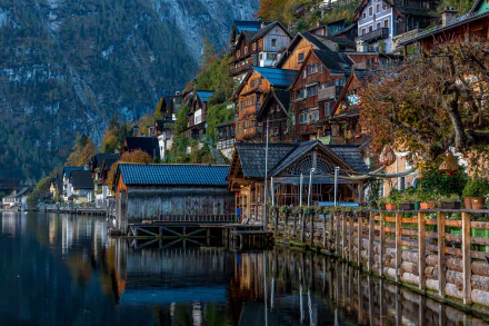 5K Ultra HD PC desktop wallpaper of Hallstatt, Austria: rows of man-made wooden houses and buildings along a lakeshore, their colorful facades mirrored in the lake's reflection.