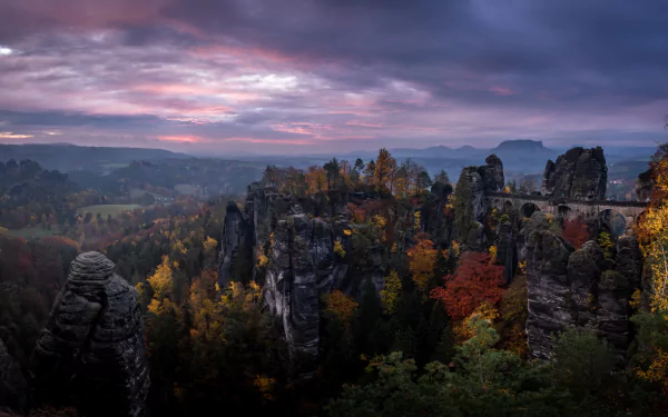 Sunset over the Elbe Sandstone Mountains in Germany, featuring the man-made Bastei Bridge amidst autumn forest colors, captured in 4K Ultra HD.