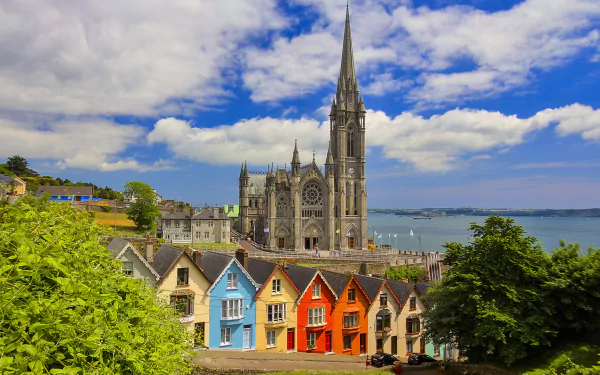 2K Quad HD PC desktop wallpaper: Irish coastal town with colorful row houses and a soaring cathedral spire — a religious landmark in Ireland.