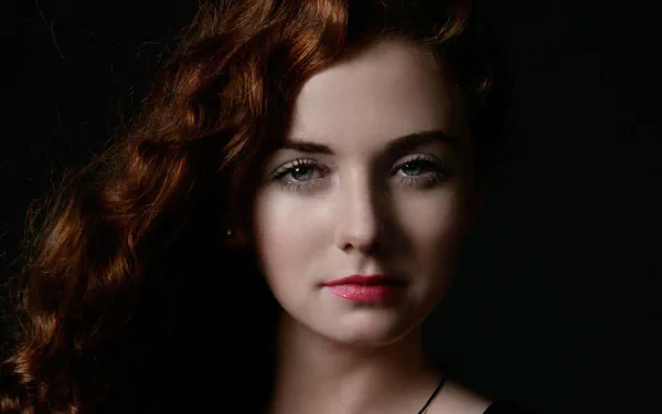 Close-up HD desktop wallpaper of Lena Katina, Russian redhead singer from t.A.T.u., with soft lighting highlighting her face against a dark background.