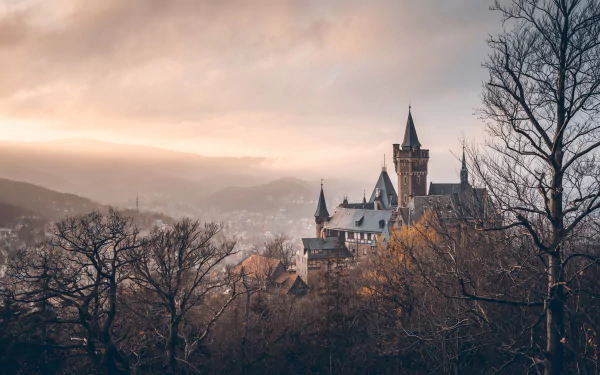 Wernigerode Castle in Germany stands majestically among autumn trees at sunset, captured in stunning 4K Ultra HD for a PC desktop wallpaper.