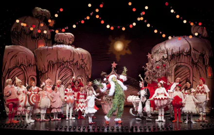 HD wallpaper of Dr. Seuss' The Grinch Musical, showing the Grinch on stage with a festive cast and holiday decorations.