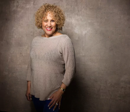 Darlene Love smiling in a beige sweater, a professional HD desktop wallpaper background.