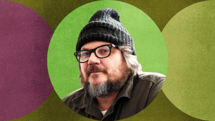 HD desktop wallpaper featuring a man in a black beanie against a vibrant, multicolored geometric background.