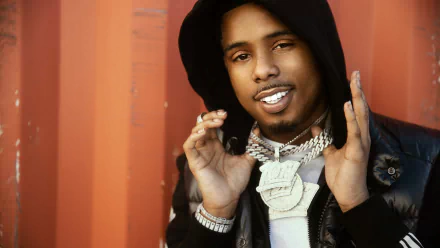 HD desktop wallpaper of a man with a black hood and jacket, adorned with shiny necklaces, posing confidently against an orange backdrop.