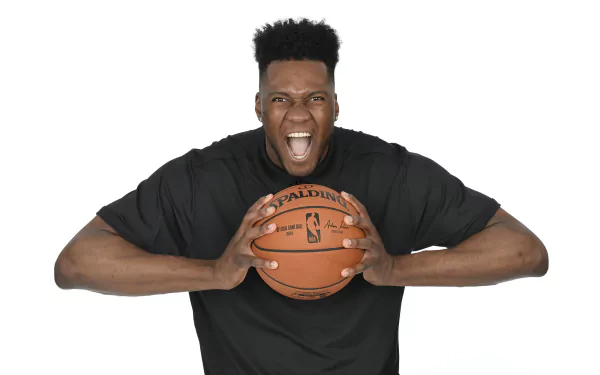 HD wallpaper of a basketball player in a black jersey holding a basketball with a fierce expression, against a white background.