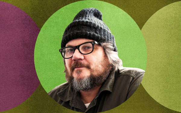 HD desktop wallpaper featuring a man in a black beanie against a vibrant, multicolored geometric background.