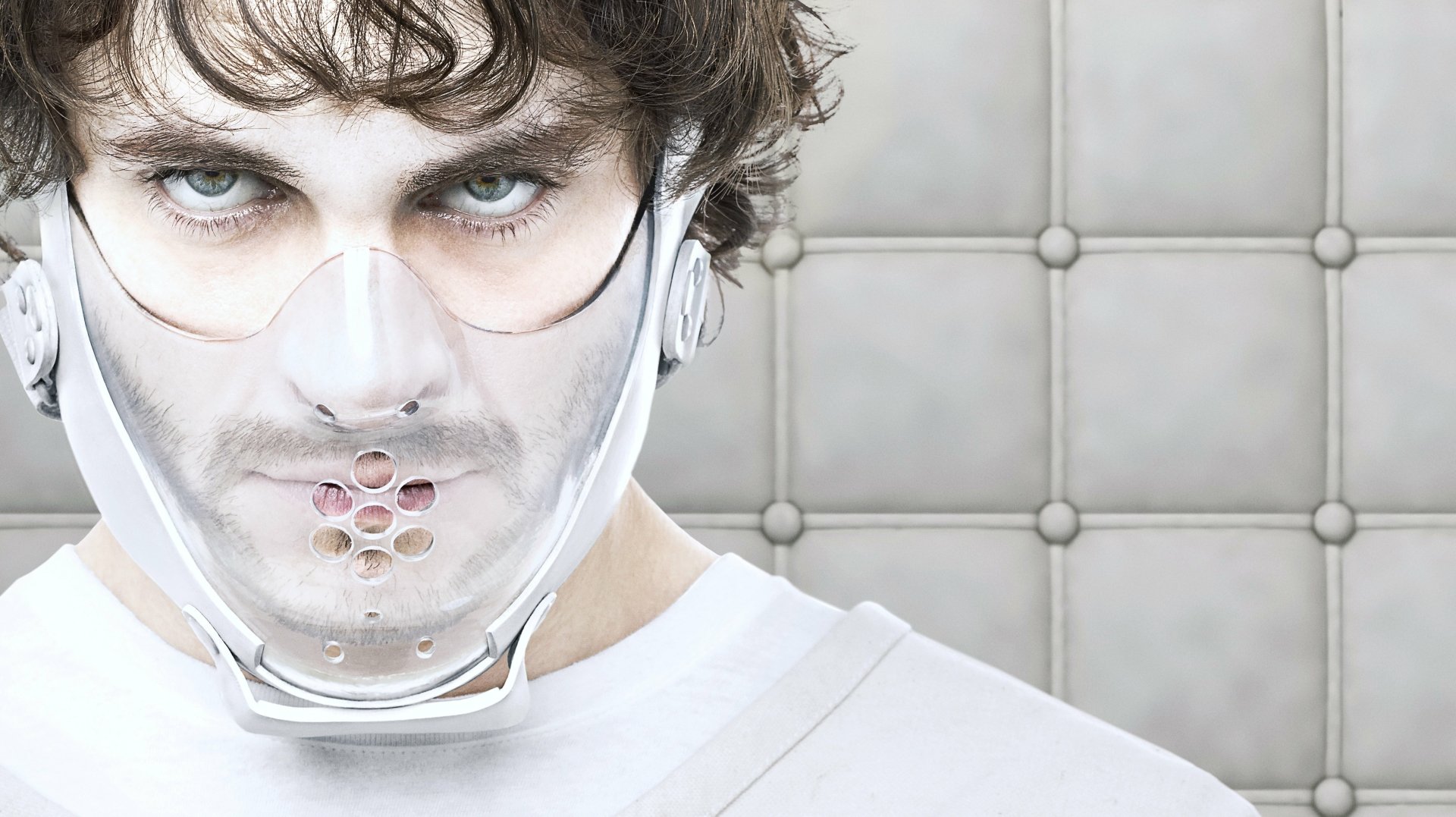 Close-up of a man wearing a restraint mask in a padded room, from the TV show Hannibal, presented as a 4K Ultra HD PC desktop wallpaper and background.