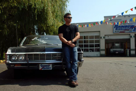 HD PC desktop wallpaper: a man in sunglasses leans against a classic black car outside a garage — Supernatural (TV Show) themed background.