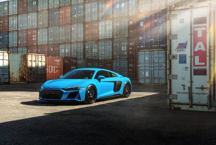 Blue Audi R8 supercar parked beside stacked shipping containers, high-detail 8K Ultra HD PC desktop wallpaper background.