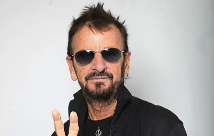 A striking HD desktop wallpaper featuring Ringo Starr, showcasing his signature peace sign gesture and cool sunglasses, capturing the essence of music and rock legends.
