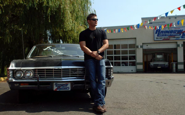 HD PC desktop wallpaper: a man in sunglasses leans against a classic black car outside a garage — Supernatural (TV Show) themed background.