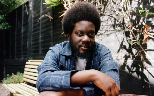 A man sitting outdoors with a thoughtful expression, serving as an HD desktop wallpaper background.