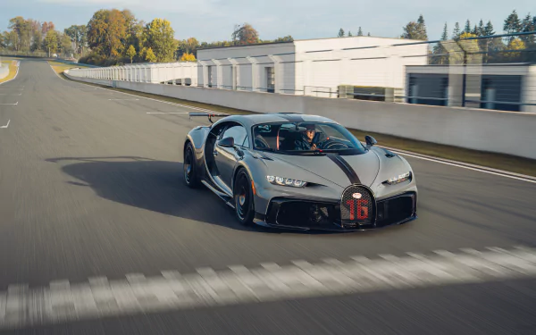 Silver Bugatti Chiron Pur Sport supercar speeding on a racetrack by pit garages — 8K Ultra HD PC desktop wallpaper background.