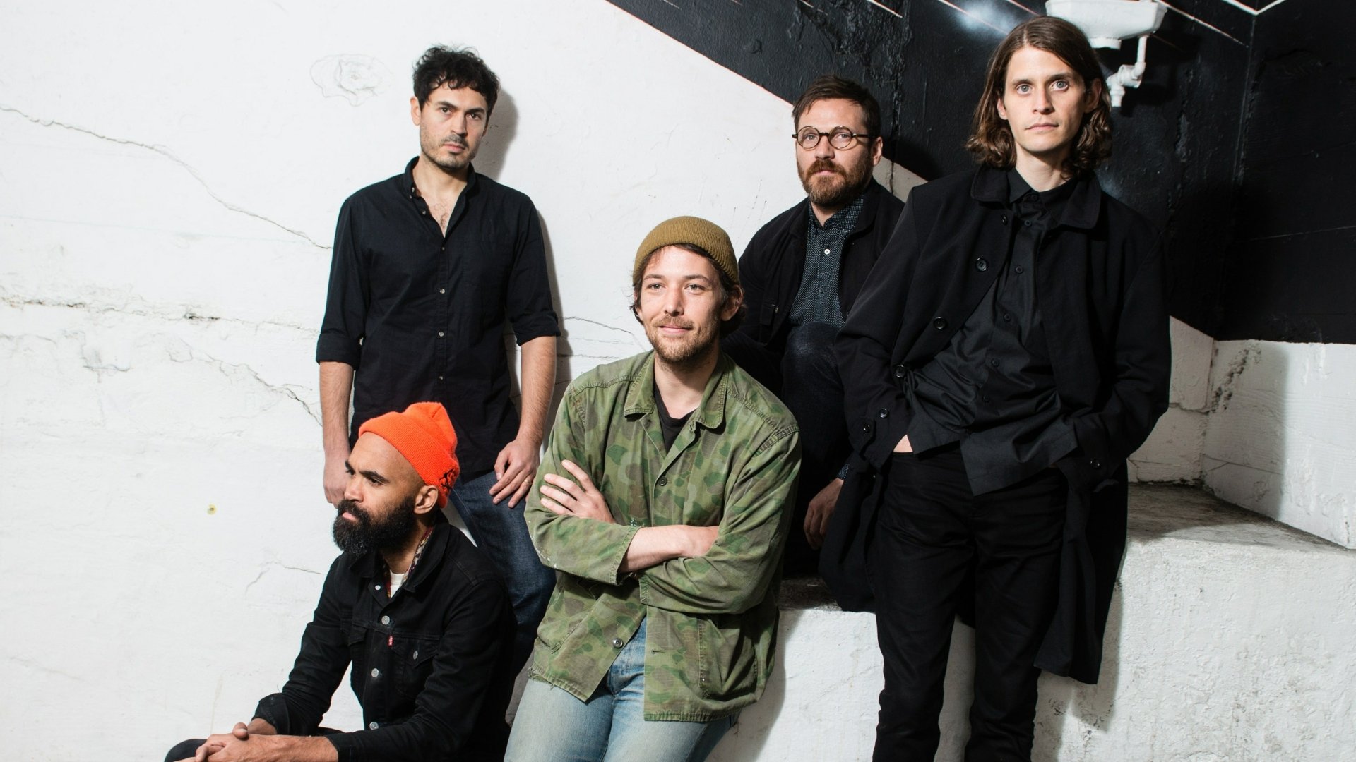HD desktop wallpaper featuring the band Fleet Foxes, with members posing against a white wall.