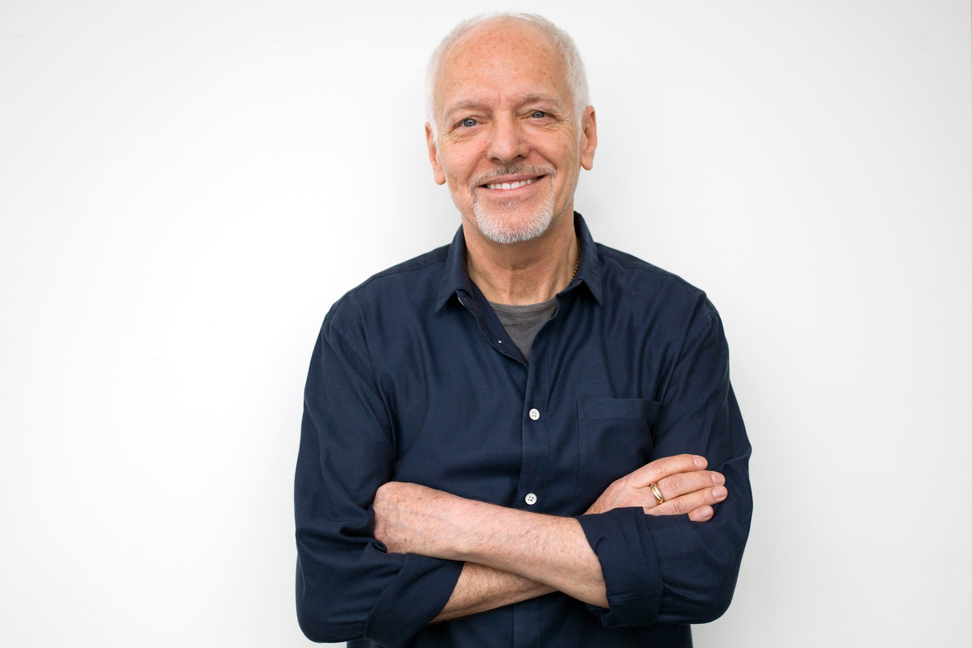 HD desktop wallpaper featuring a smiling man with his arms crossed against a white background.