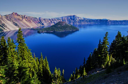 A stunning 4K Ultra HD view of Crater Lake in the USA, featuring a serene island surrounded by deep blue water and lush green forests.
