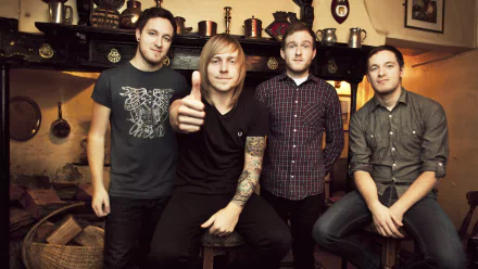 HD desktop wallpaper featuring a group of four men, casually dressed, posing together indoors, evoking a congenial atmosphere.