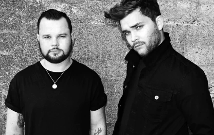 Black and white HD wallpaper featuring the band Royal Blood, showcasing the duo in contemporary attire against a textured background, embodying their music's bold aesthetic.