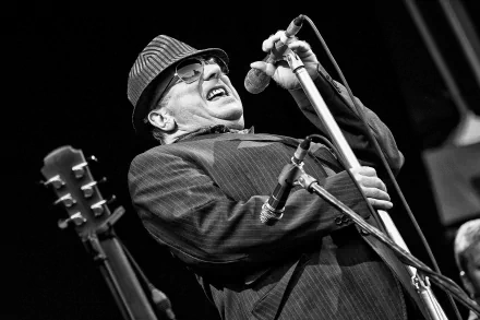 Black and white HD wallpaper of a singer performing on stage with a microphone, wearing a suit and hat, conveying a sense of soulful music.