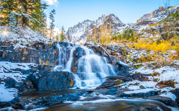 4K Ultra HD desktop wallpaper featuring a serene waterfall cascading over rocky terrain in a snowy mountain landscape of California, USA.