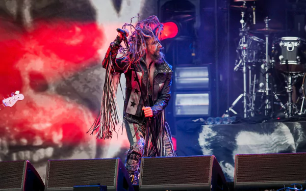 A high-definition desktop wallpaper featuring Rob Zombie performing passionately on stage, surrounded by vibrant visuals and musical elements, capturing the essence of his music.