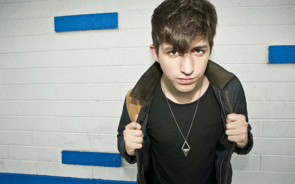 HD desktop wallpaper featuring a man with a jacket and necklace against a white brick wall with blue stripes.