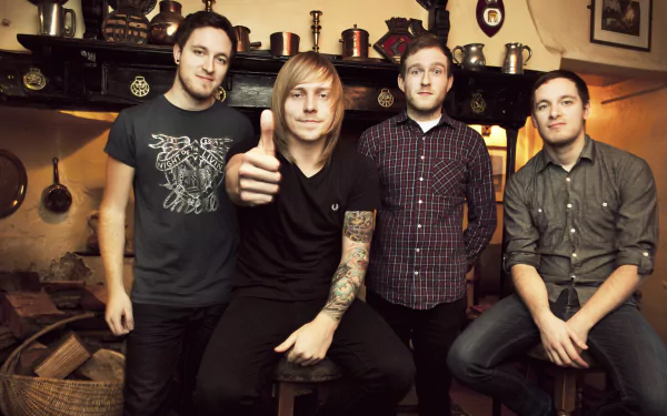 HD desktop wallpaper featuring a group of four men, casually dressed, posing together indoors, evoking a congenial atmosphere.