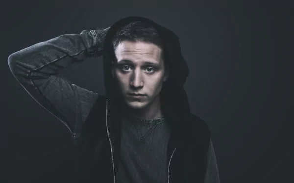 A moody HD desktop wallpaper featuring a contemplative young man in a hoodie against a dark background, capturing the essence of music and NF's artistic vibe.