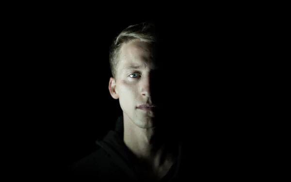 HD desktop wallpaper featuring a mysterious man with a subtle glow on his face set against a dark background, tagged with NF.