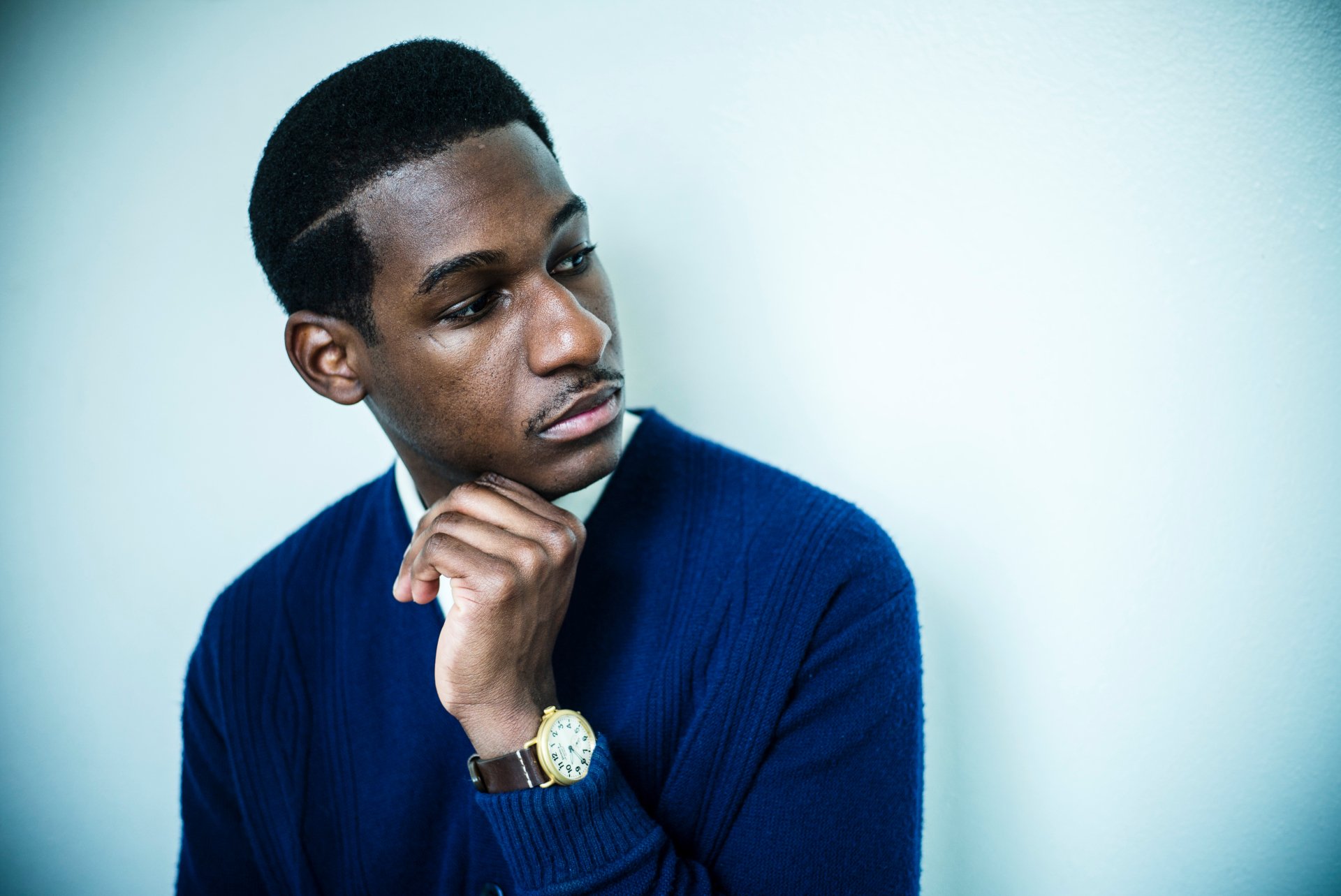 HD desktop wallpaper of a contemplative man in a blue sweater, serving as a background image, tagged as Leon Bridges.