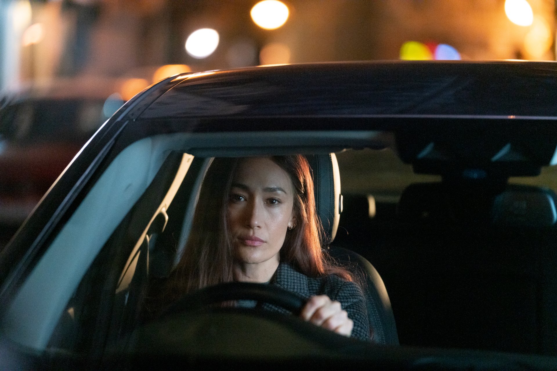 Maggie Q in a scene from the movie The Protégé, shown driving a car at night in this HD PC desktop wallpaper and background.
