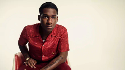 Stylish man seated in a red shirt for an HD desktop wallpaper background.