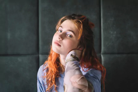 HD desktop wallpaper featuring a contemplative person with auburn hair against a dark tufted background, embodying a pensive and artistic vibe.