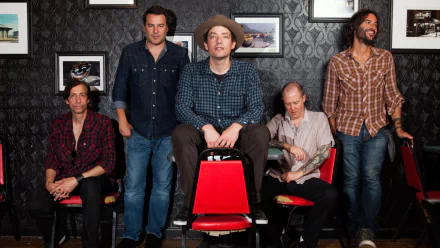 HD desktop wallpaper featuring a group of five men posing casually, tagged as The Wallflowers, with patterned wallpaper in the background.