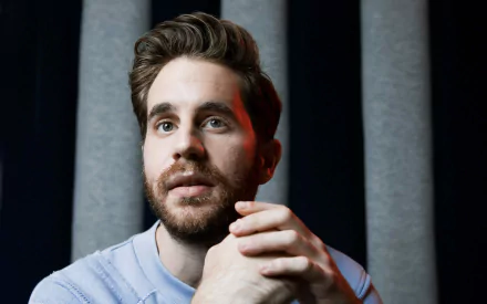 HD desktop wallpaper featuring a contemplative individual with a beard, against a backdrop with vertical lines.