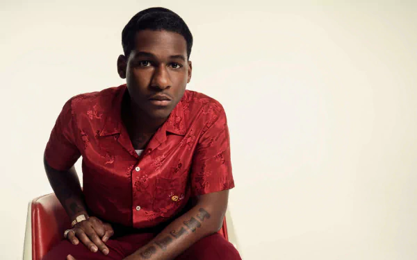 Stylish man seated in a red shirt for an HD desktop wallpaper background.