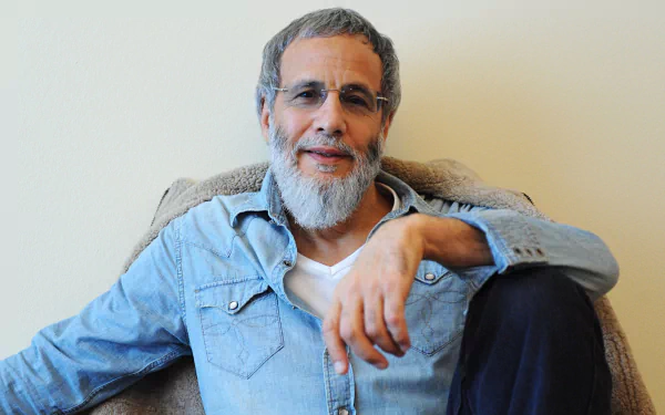 A relaxed individual sitting on a couch, posing for a HD desktop wallpaper with a tag 'Cat Stevens'.