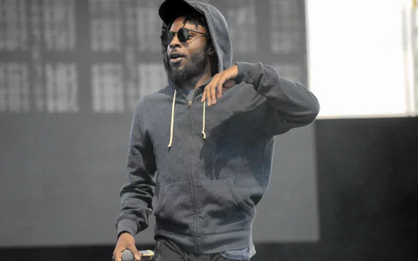 HD desktop wallpaper featuring a man in a hoodie performing on stage, representing Isaiah Rashad.