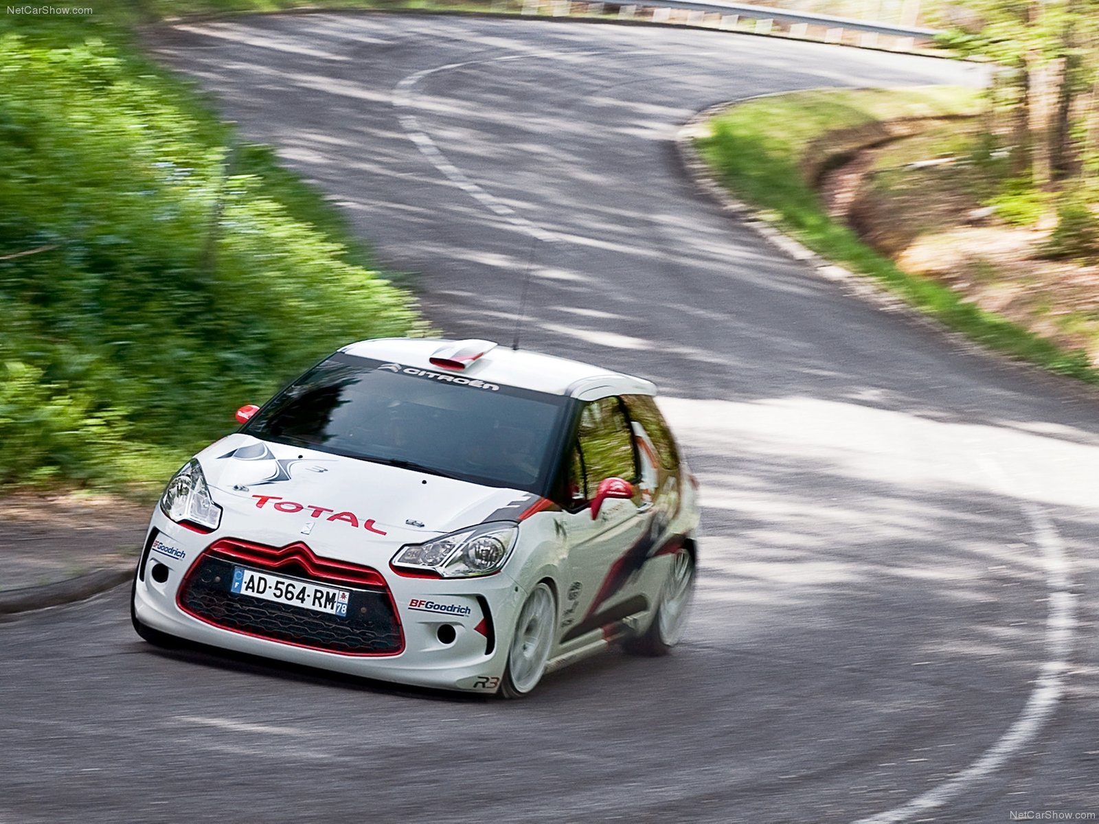 Citroen DS3 R3 sports car racing on a white road, with a sleek red and white design.