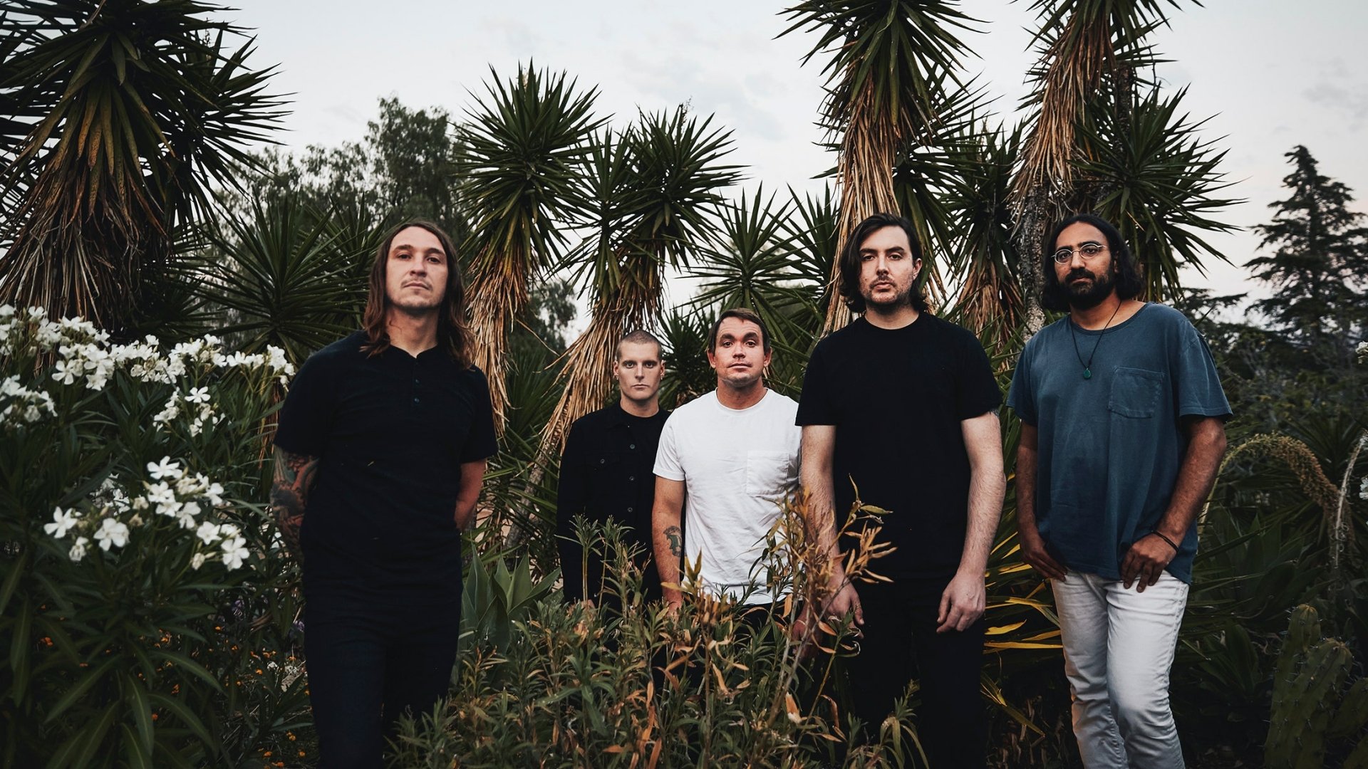 HD desktop wallpaper featuring a group of five band members standing confidently outdoors with tropical plants in the background, tagged with Deafheaven.