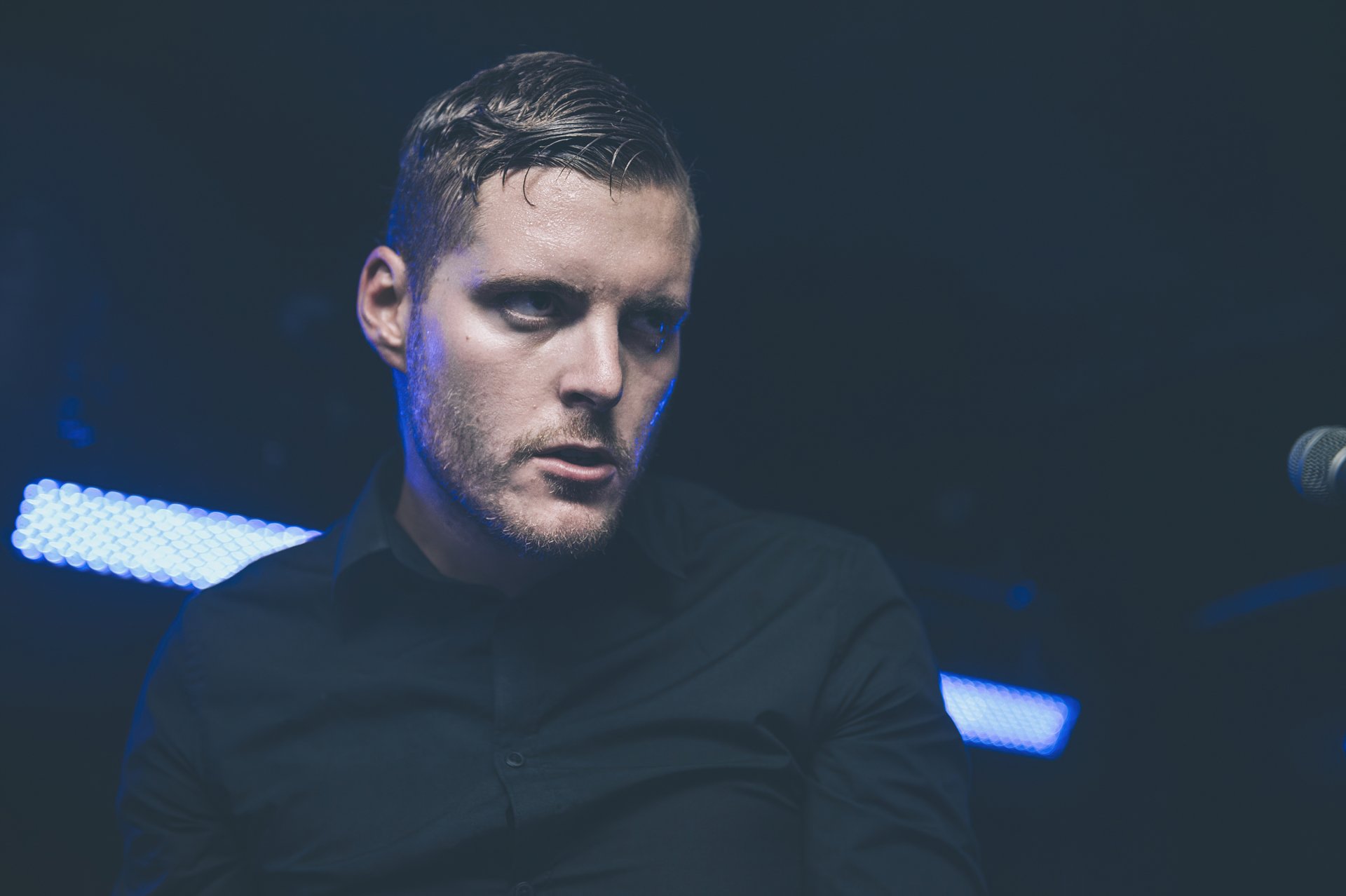 HD wallpaper featuring a member of Deafheaven performing, with a moody blue stage lighting background.