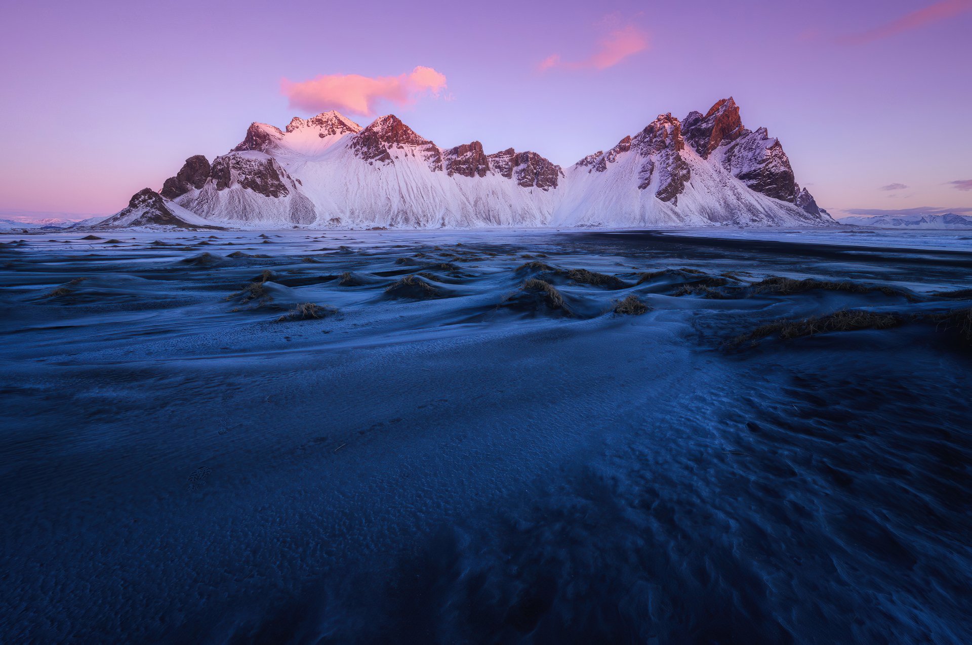 4K Ultra HD PC desktop wallpaper of Vestrahorn nature: snow-capped jagged peaks glowing pink at sunrise above a rippled black sand foreground.