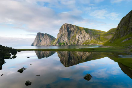 A 4K Ultra HD photo of Norway's Lofoten mountains mirrored in calm water, showcasing vivid reflection and serene natural beauty.